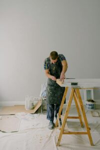 Craftsman focusing intently on creating wooden furniture in an indoor workshop.